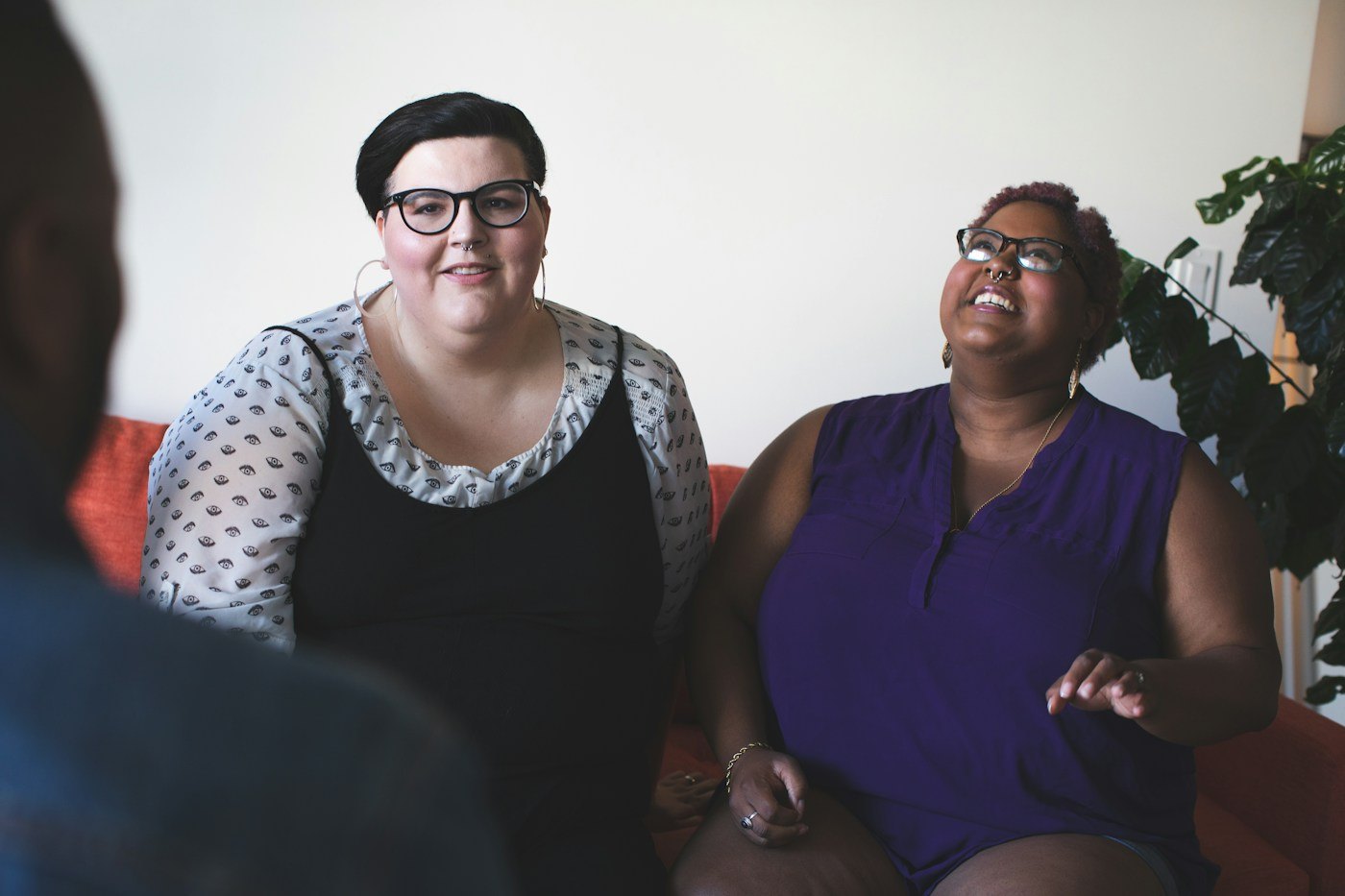 Two women laughing together while sitting on a sofa