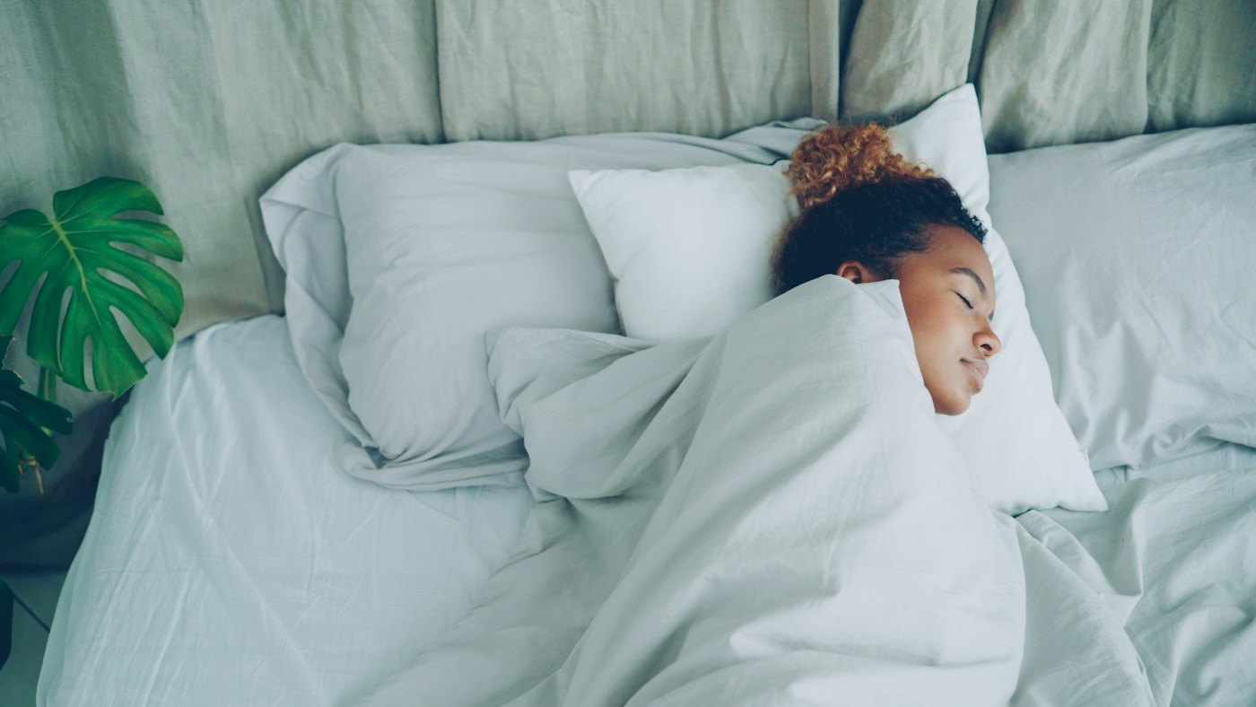 Woman asleep beneath white bedding