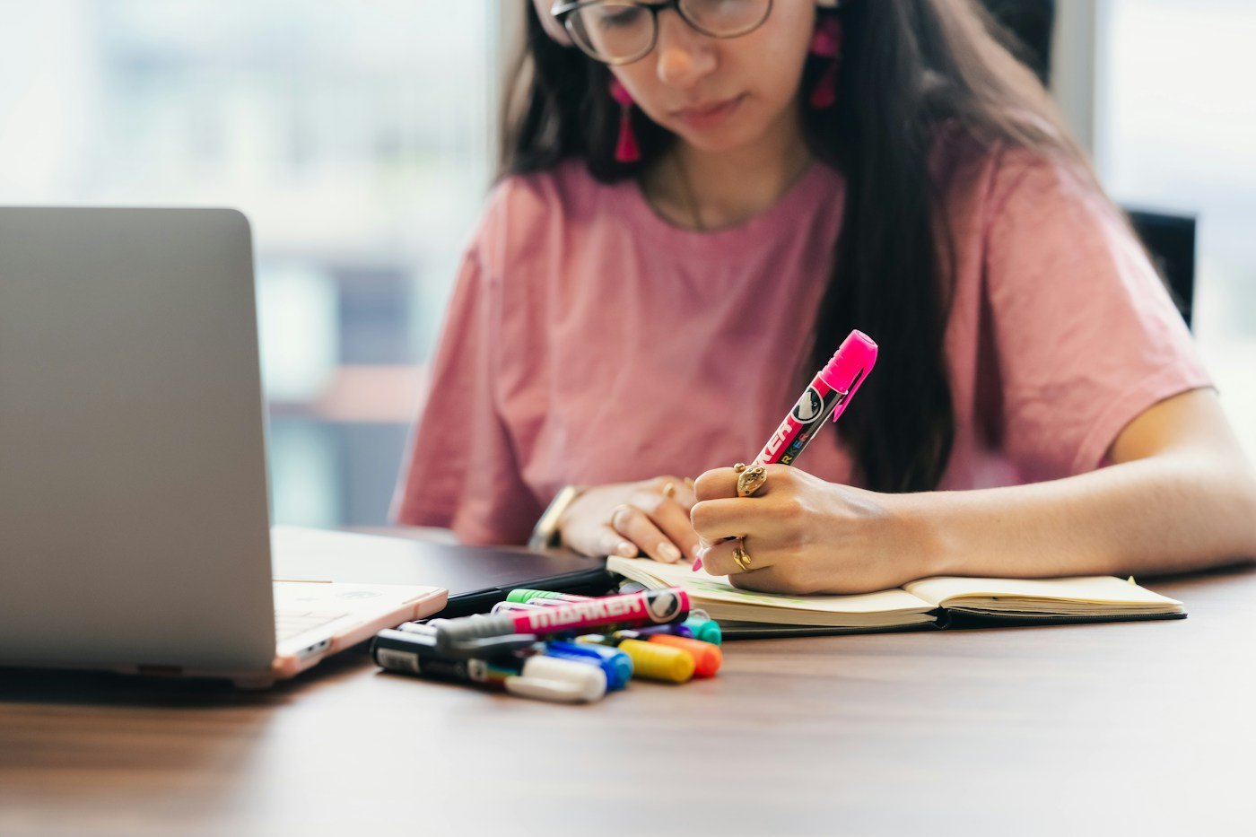 Woman writing notes beside a laptop at a table